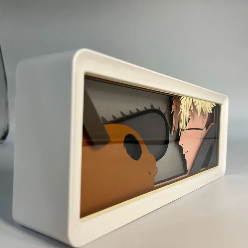 Lampe Décorative Chainsaw Man | Boîte lumineuse avec design en papier découpé représentant le visage de Denji et Pochita. Parfaite pour décorer une chambre ou un bureau, cette lampe offre une ambiance unique pour les fans de manga et d'anime